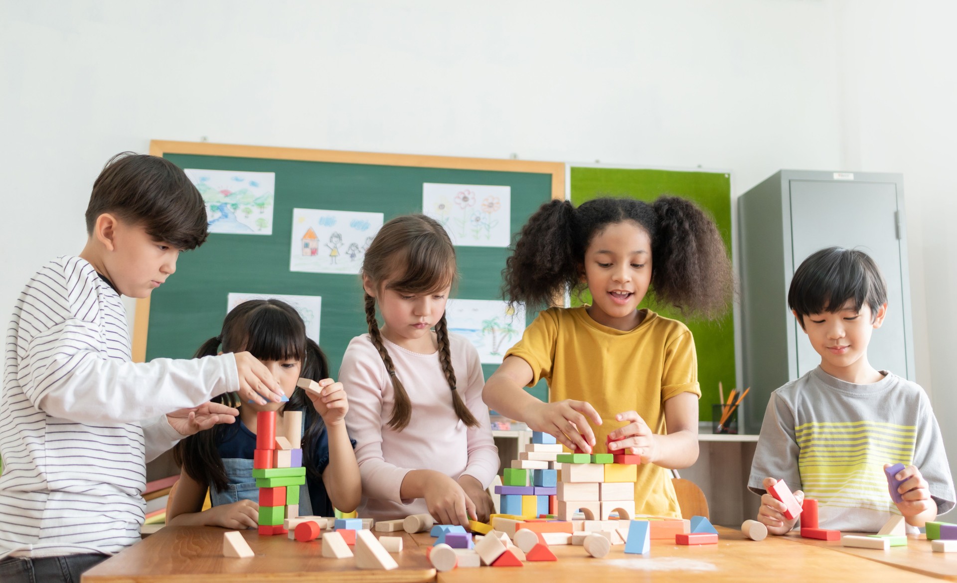 Multi ethnic Elementary School Pupils playing wooden block toys